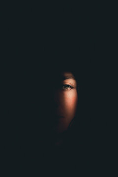 A sliver of light falls upon a woman's face.