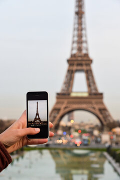 Woman taking photos with a smartphone to the Eiffel Tower