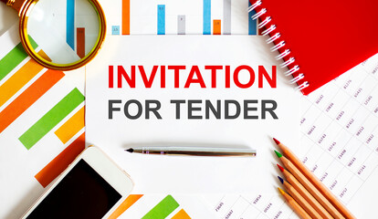 Text INVITATION FOR TENDER on the notepad with office tools, pen on financial report