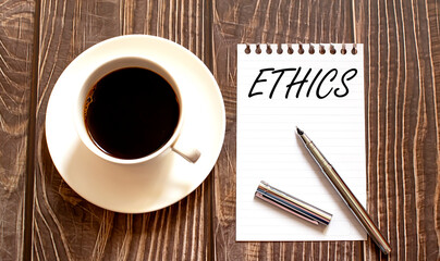 ETHICS - white paper with pen and coffee on wooden background