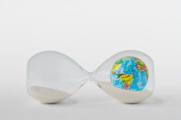 Hourglass with planet earth lying on the background - Concept of time and planet earth