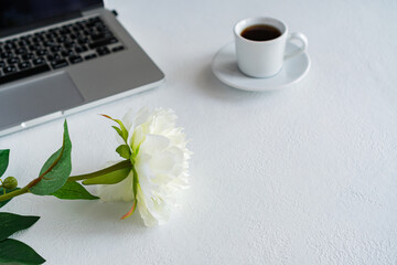 there is a laptop, a coffee mug and a flower on the table