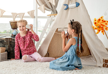 Little sisters playing with homemade telephone © tan4ikk