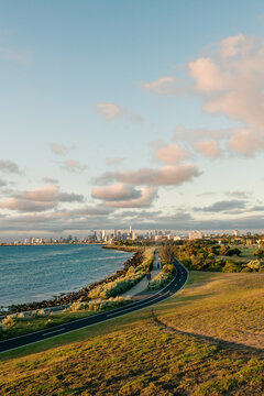 city skyline with a park and bay in the foreground, with some people taking a late afternoon stroll