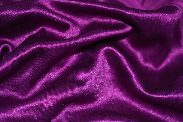 Fototapeta na wymiar Bright colorful, rich velvet purple background with overflow and ebb. An unusual shaggy purple fabric with curves and waves is located on a flat surface, an unusual look.