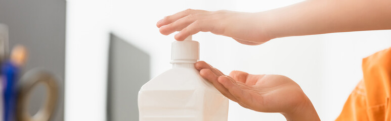 Horizontal image of boy using hand sanitizer in classroom