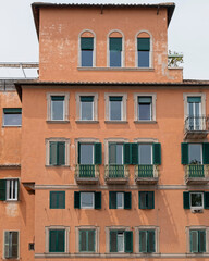 Fototapeta na wymiar orange walls house front with green windows, Rome Italy