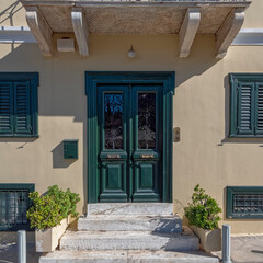 Fototapeta na wymiar vintage house front with green door and windows by the sidewalk, Athens Greece