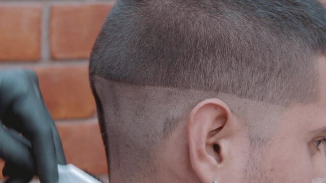 Barbero afeitando cráneo de modelo masculino en barbería con máquina de afeitar o también llamada marcadora
