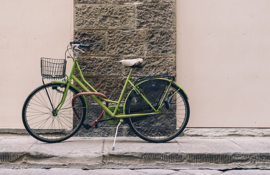 Green bicycle with basket parked on the sidewalk