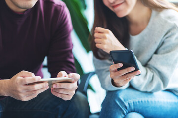 Young people using and playing games on mobile phone while sitting together