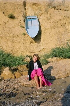 A film portrait of young smiling woman with a boat on background