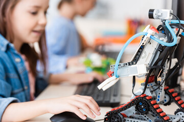 Fototapeta na wymiar Selective focus of robot near schoolgirl using computer in school