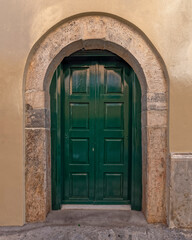 Fototapeta na wymiar dark green painted door with arched stone frame