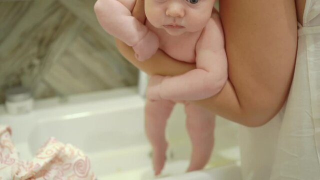 mother washes baby in bathroom sink. skin care for newborns and changing diapers