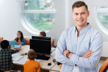 Selective focus of teacher looking at camera near schoolkids in stem school