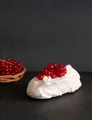 Obraz na płótnie Canvas Mini Pavlova with whipped cream and redcurrant. Meringue dessert. dark background, front view