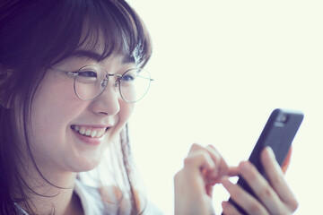 スマートフォンを操作するメガネをかけた女性