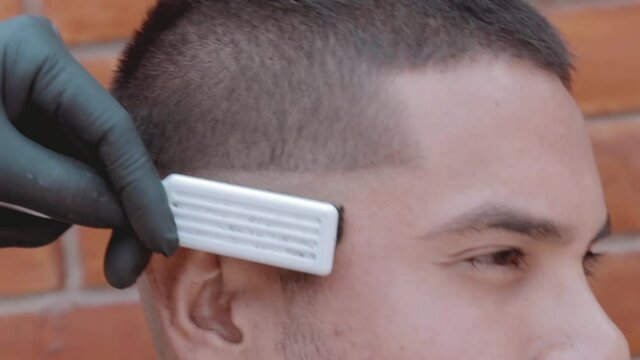 Barbero usando maquina de afeitar y cepillo de peluquer&iacute;a en modelo masculino en peluquer&iacute;a