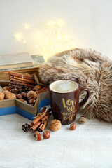 coffee Cup, nuts, cinnamon, and fur plaid. autumn or winter cozy composition. home hygge comfort concept. 