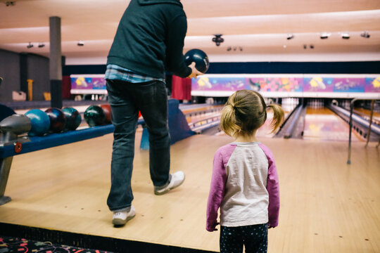little girl watches man bowling