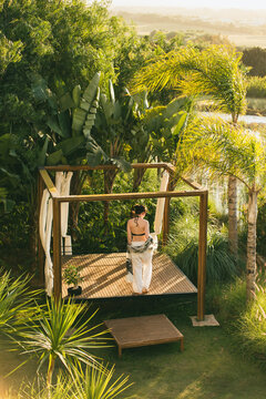 A brunette holiday maker walking on a picturesque patio surrounded by tropical plants