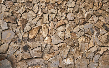 Wall of wild stone. The walls are finished with ocher stone tiles. Fortress effect. Close up, with...