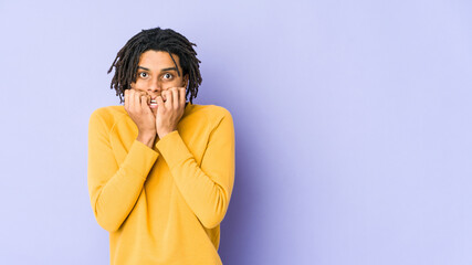 Young black man wearing rasta hairstyle biting fingernails, nervous and very anxious.