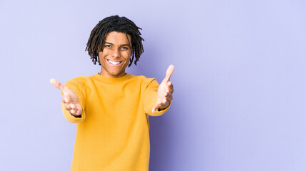Young black man wearing rasta hairstyle showing a welcome expression.