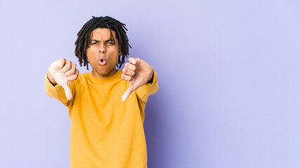 Young black man wearing rasta hairstyle showing thumb down and expressing dislike.