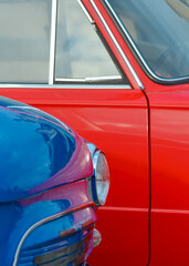 Fototapeta premium Headlight of a blue vintage car on the background of a red car close-up