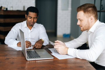 Business team of two multiethnic businessmen people in formalwear sitting together at office desk...