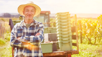 Winegrower or winemaker in front of tractor in vineyard