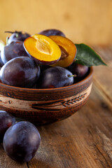 Blue plum in a bowl on a wooden table. Plums in a cut. Top view, place for text. Fruit background with copy space. Still life food.