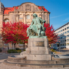 Obraz premium Statue of great scientist Otto von Guericke in red and golden Autumn colors in historical downtown of Magdeburg Germany, at sunny day and blue sky, closeup, details..