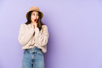 Young caucasian woman isolated on purple background praying for luck, amazed and opening mouth looking to front.