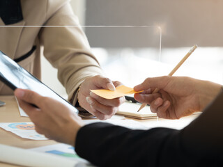 Close up woman's hand passing sticky note businessman through partition.  New Normal lifestyle for protection.