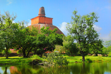Fototapeta na wymiar Ancient Mirisaveti stupa, lake, green trees and blue sky in Anuradhapura, Sri Lanka