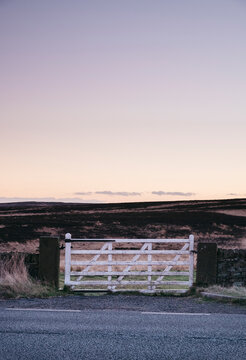 White gate leading to moorland at twilight. Derbyshire, UK.