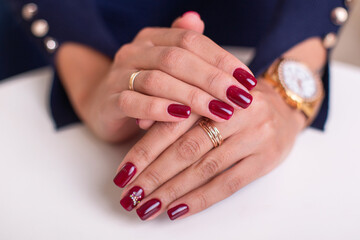 Close up view of beautiful female hands with luxury manicure nails, wine red gel polish, on white background