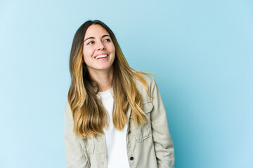 Young caucasian woman isolated on blue background relaxed and happy laughing, neck stretched showing teeth.