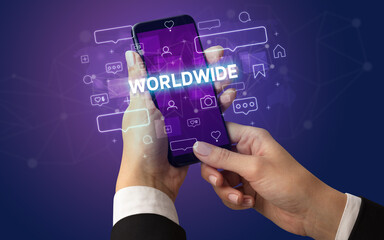 Female hand typing on smartphone with WORLDWIDE inscription, social media concept