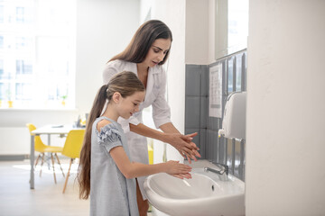 Obraz premium Doctor showing how to clean hands to the long-haired girl