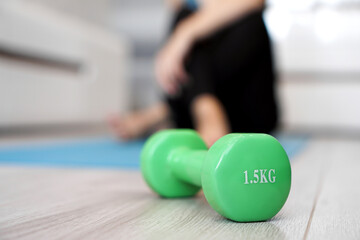 Fototapeta na wymiar Close up of dumbbell and woman stretching in blurred background. Healthy lifestyle concept