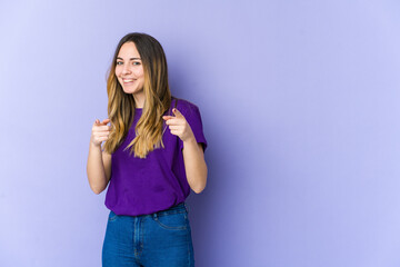 Fototapeta premium Young caucasian woman isolated on purple background pointing to front with fingers.