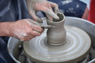 Detail with hands of an artist modeling a bowl on a pottery wheel