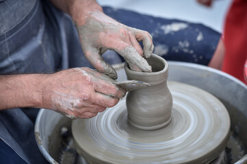 Detail with hands of an artist modeling a bowl on a pottery wheel