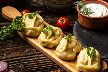 Uzbek prepared boiled Manti or manty dumplings in a traditional bowl on wooden table. menu recipe place for text