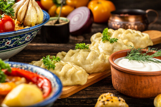 Uzbek prepared boiled Manti or manty dumplings in a traditional bowl on wooden table dishes of Uzbek cuisine lagman, pilaf