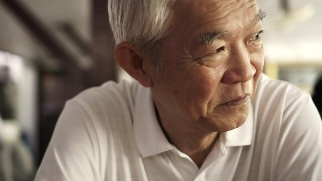 Asian senior elder man sitting looks happy in retro sepia tone close up shot